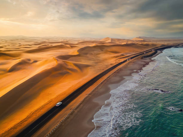 Aerial top view of street road with Namib Desert Safari, sand dune, coast sea in Namibia, South Africa. Natural landscape background at sunset. Famous tourist attraction. Sand in Grand Canyon