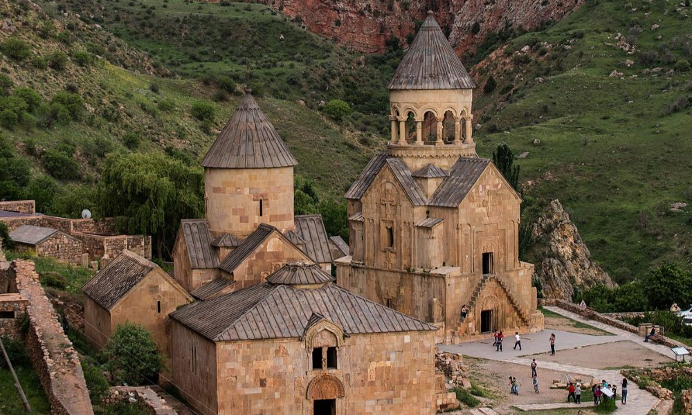 The unique stone facades, intricate carvings, and conical domes of the medieval Noravank Monastery in Armenia nestled within a rugged mountain canyon during a luxury private heritage tour with Lux Orient.