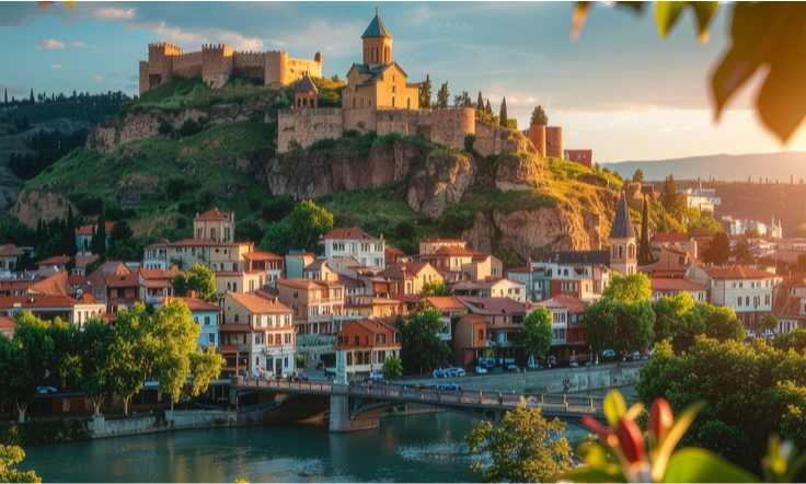 An elevated scenic view of the old town buildings and Metekhi Church below the ancient Narikala Fortress along the Kura River in Tbilisi, Georgia during a luxury private city tour with Lux Orient.