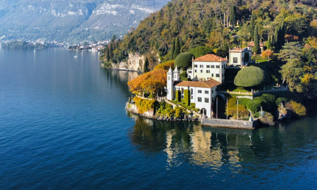 The famous stone loggia and manicured ivy-covered arches of Villa del Balbianello overlooking the calm waters of Lake Como during a bespoke luxury private tour with Lux Orient.