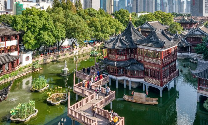 The historic two-story Huxinting Teahouse sitting over a green pond next to the zigzagging stone Nine-Turn Bridge at Yu Garden in Shanghai during a bespoke luxury private tour with Lux Orient.