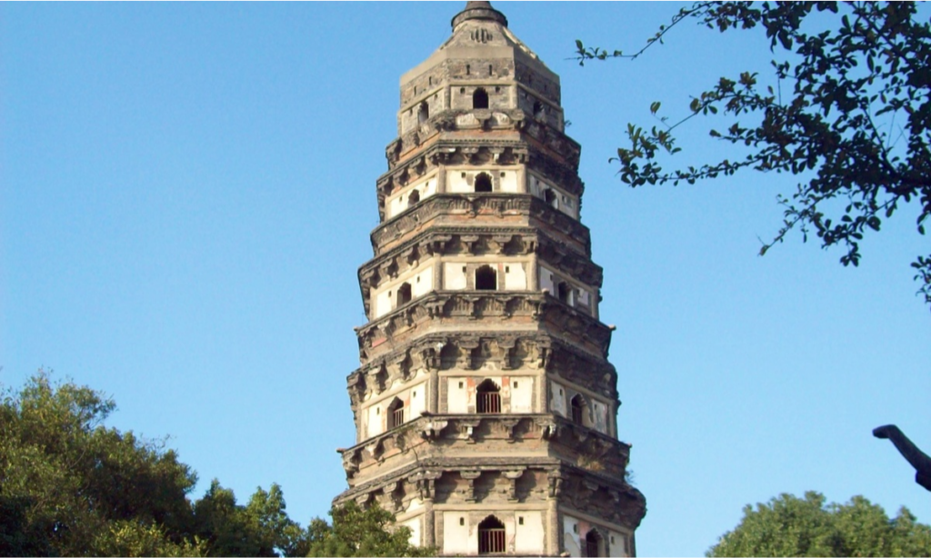 The ancient seven-story, octagonal brick Cloud Rock Pagoda tilting against a blue sky on Tiger Hill in Suzhou during an exclusive bespoke luxury heritage tour with Lux Orient.