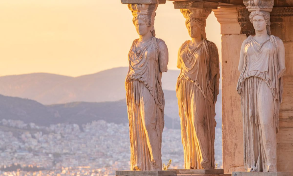 Three beautifully carved marble Caryatid female statues acting as supporting columns on the Erechtheion porch at the Acropolis of Athens during a bespoke luxury private tour with Lux Orient.