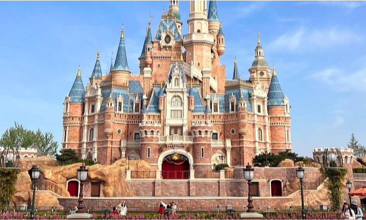 A panoramic twilight view of an illuminated theme park garden at Shanghai Disney Resort, highlighting the premium, all-inclusive private VIP concierge tour packages offered by Lux Orient.