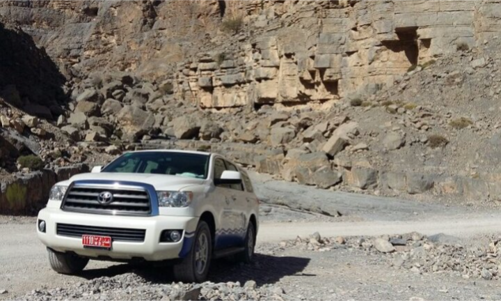 A convoy of luxury modified 4x4 Jeep vehicles traversing a steep mountain pass near the limestone summit of Jebel Harim in Musandam, Oman, on a private VIP off-road safari arranged by Lux Orient.