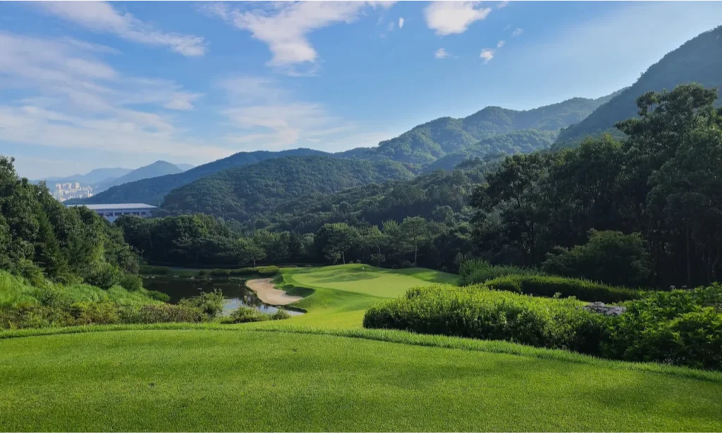 The sweeping, vibrant green fairways and meticulously sculpted sand traps of the coastal Haevichi Country Club in Jeju Island, South Korea, overlooking the ocean during a premium private luxury sports tour with Lux Orient.