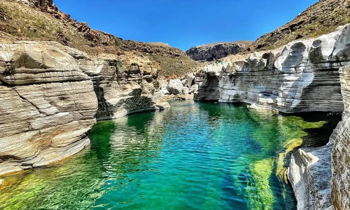 The crystal-clear malachite green freshwater swimming pools of Kilisan Canyon framed by massive white boulders and unique bottle trees on Socotra Island, Yemen, during an exclusive private luxury excursion with Lux Orient.