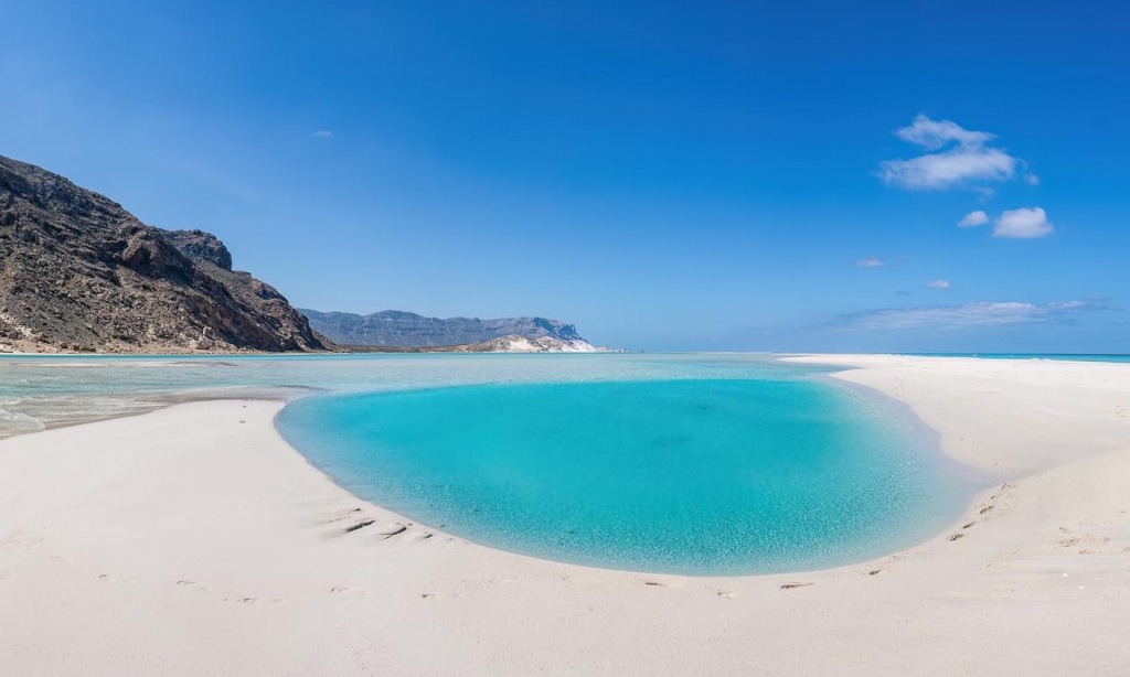 The endless, smooth white sand dunes and crystal-clear azure waters of Aomak Beach under a bright sun on Socotra Island, Yemen, during an exclusive private luxury tour with Lux Orient.