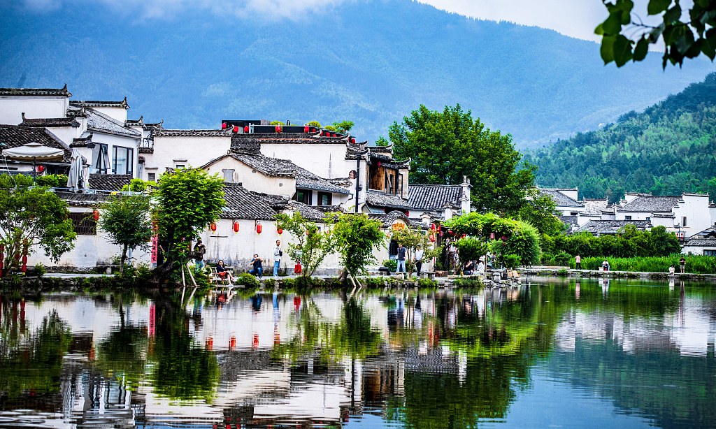 The traditional white-walled and black-roofed houses of Hongcun Village reflecting perfectly in the still water of the historic Moon Pond near Huangshan, during an elite private luxury tour with Lux Orient.