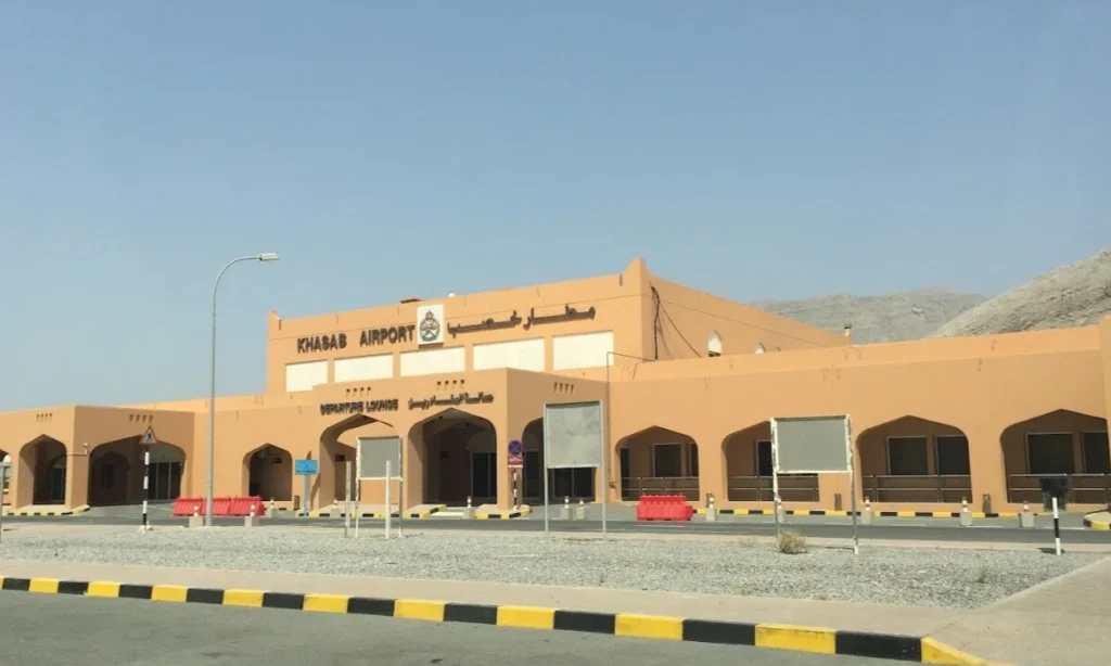 The runway and terminal building of Khasab Airport surrounded by the dramatic, arid Hajar mountain peaks of Musandam, Oman, during a private luxury VIP arrival transfer with Lux Orient.