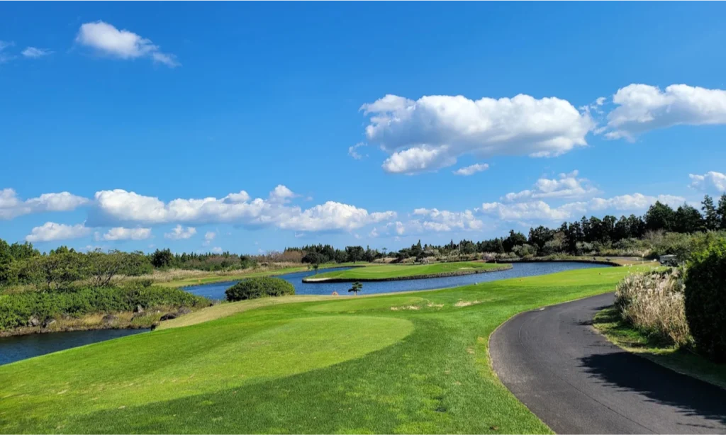 The sweeping, vibrant green fairways and meticulously sculpted sand traps of the coastal Haevichi Country Club in Jeju Island, South Korea, overlooking the ocean during a premium private luxury sports tour with Lux Orient.