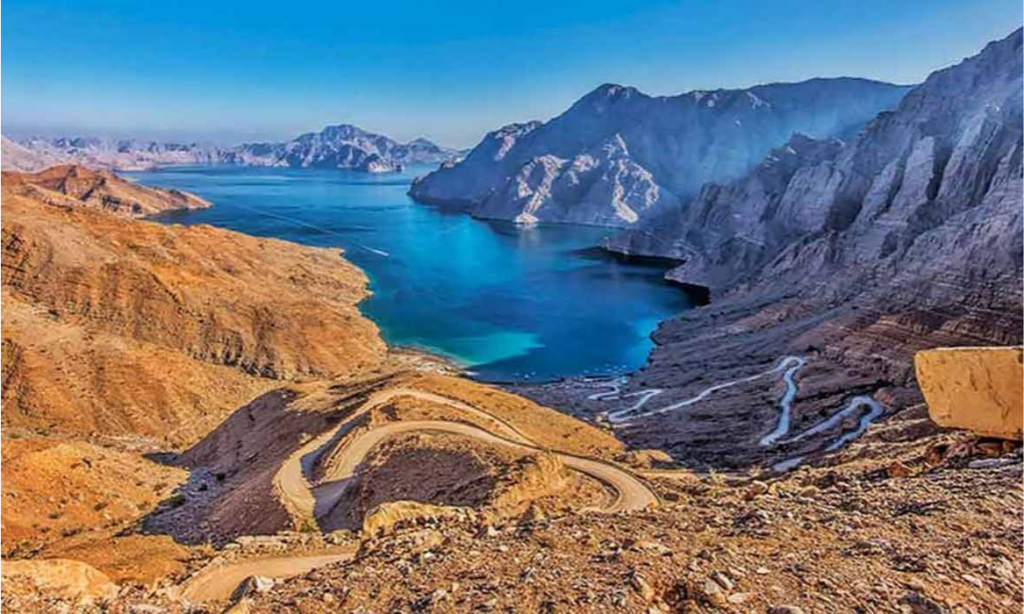 A premium luxury 4x4 safari vehicle navigating a rugged dirt road high along the steep, rocky ridges of Jebel Harim mountain in Musandam, Oman, during a private VIP off-road tour with Lux Orient.