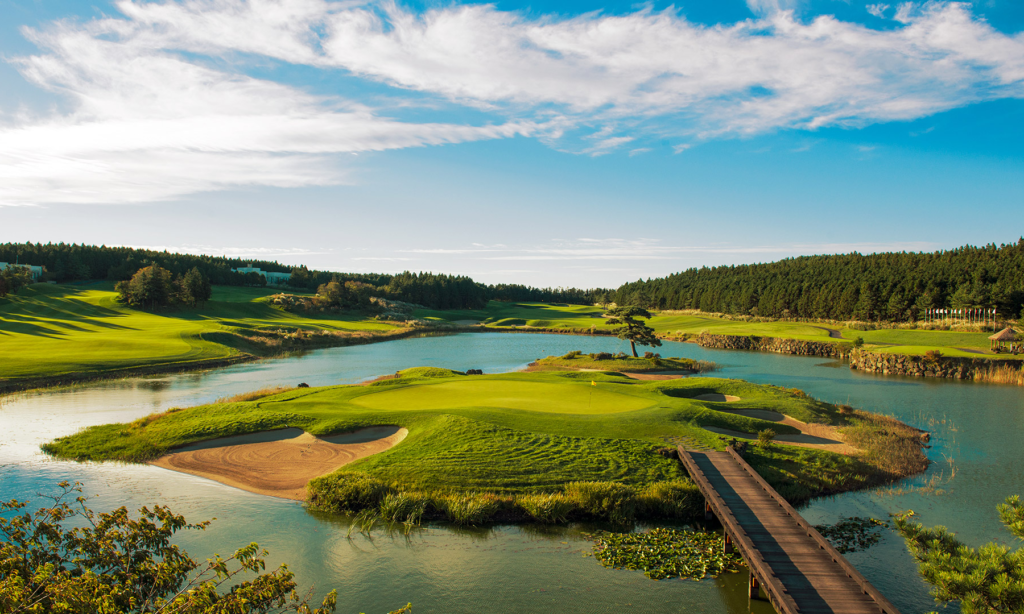 A sweeping view of the pristine, manicured green fairways, sand traps, and scenic water hazards at the exclusive Club at Nine Bridges on Jeju Island, South Korea, during a luxury private golf holiday with Lux Orient.