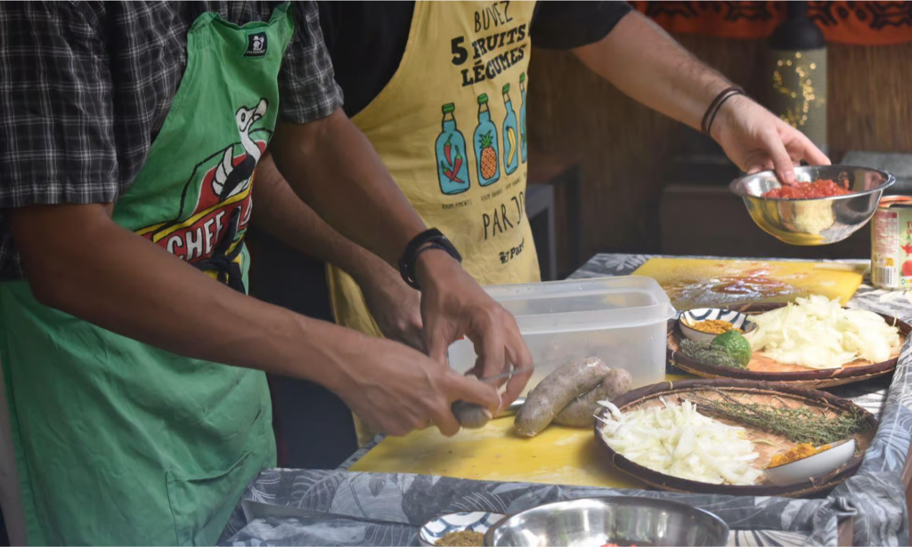 A private chef demonstrating traditional Creole culinary techniques with colorful island spices, a stone pestle and mortar, and simmering copper pots in La Réunion, during an exclusive private luxury cooking masterclass with Lux Orient.