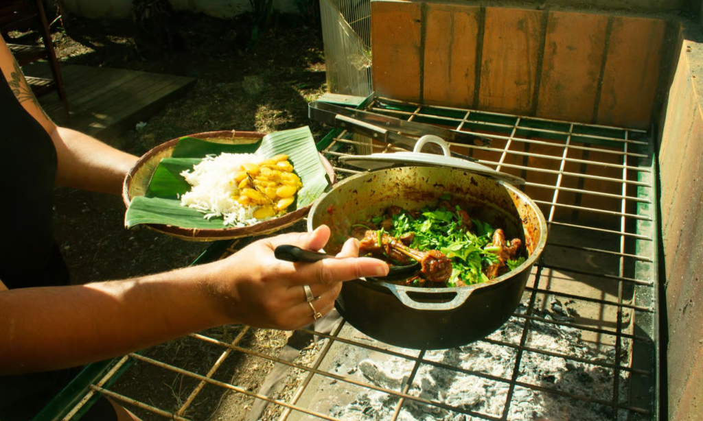 A private chef demonstrating traditional Creole culinary techniques with colorful island spices, a stone pestle and mortar, and simmering copper pots in La Réunion, during an exclusive private luxury cooking masterclass with Lux Orient.