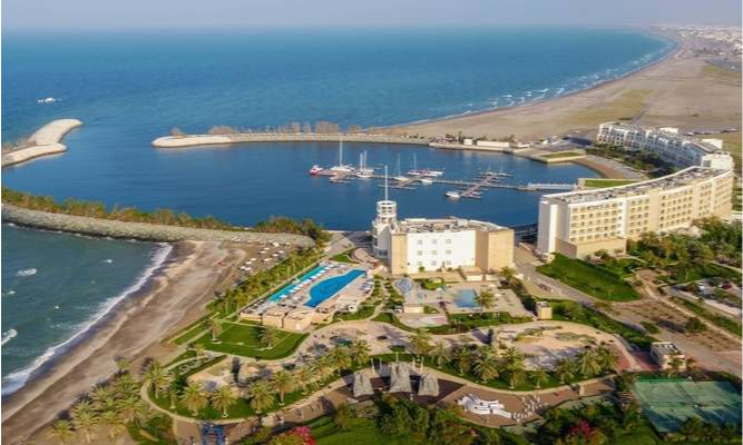 A high-angle panoramic view of the crescent-shaped luxury marina and beach resort at Al Musannah, Oman, during a private VIP coastal sailing tour with Lux Orient.