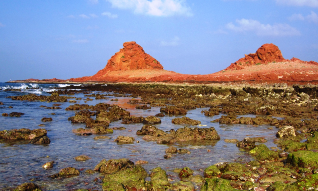 Two distinctive red volcanic rock mounds of Dihamri Marine Protected Area rising above the clear turquoise sea on Socotra Island, Yemen, during an exclusive private luxury snorkeling tour with Lux Orient.