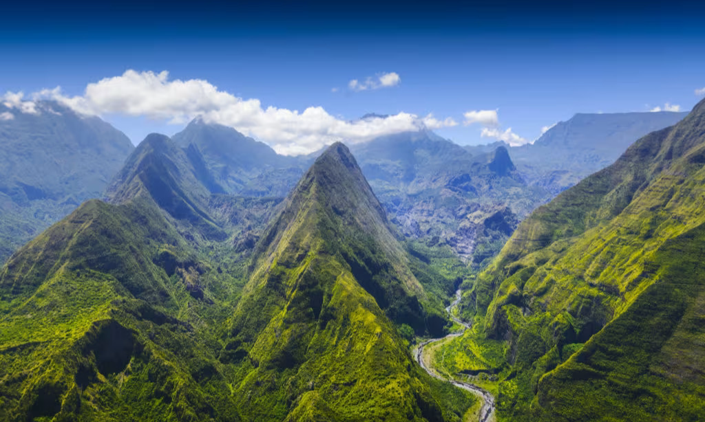 The sheer vertical green cliffs and deep ridges of the isolated Cirque de Mafate volcanic amphitheater in La Réunion, captured during an elite private luxury helicopter tour with Lux Orient.