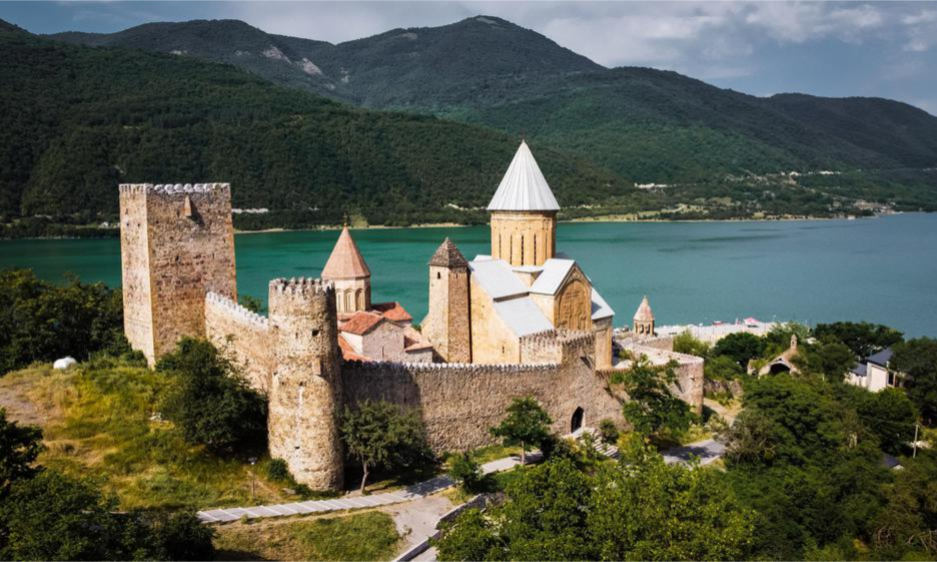 The historic stone defense towers and domed churches of Ananuri Fortress overlooking the scenic turquoise waters of the Zhinvali Reservoir in Georgia during a luxury private day tour with Lux Orient.
