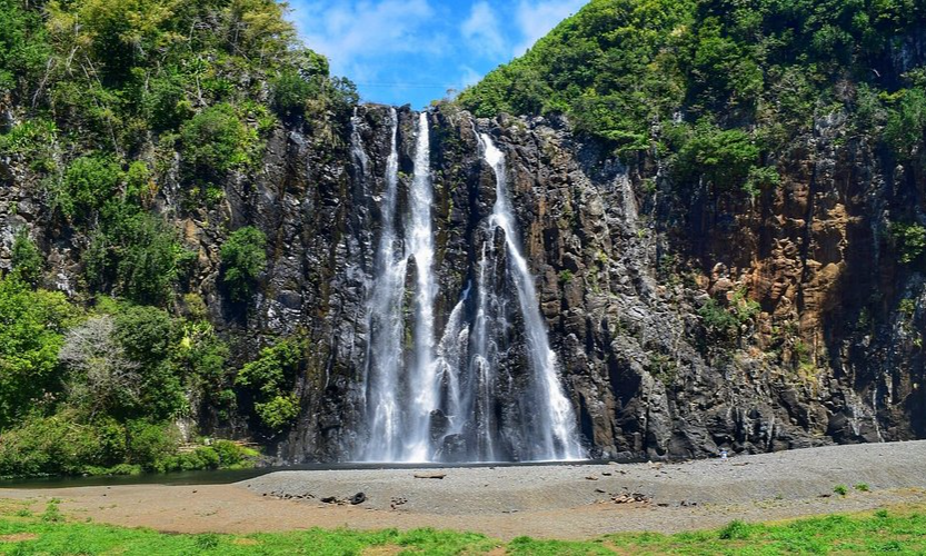The dramatic, roaring white waters of Cascade Niagara waterfall cascading down a lush, green volcanic cliff into a natural pool in Sainte-Suzanne, La Réunion, during an exclusive private luxury tour with Lux Orient.