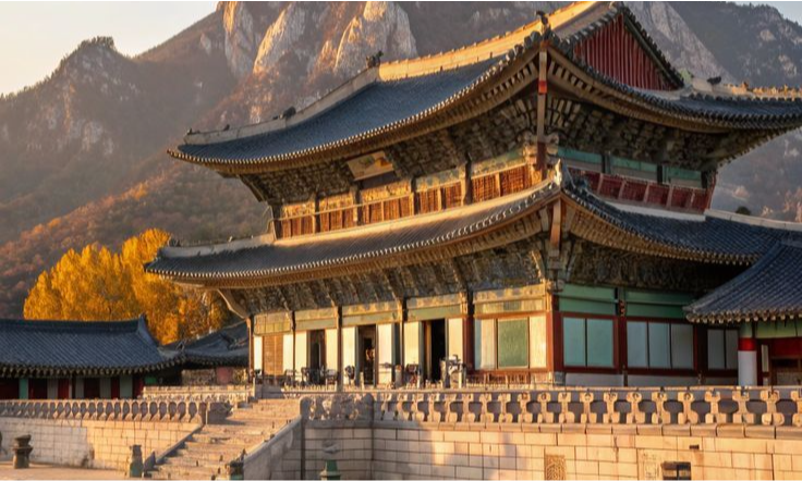 The intricate multi-colored wooden eaves, stone courtyard, and grand throne hall architecture of the historic Gyeongbokgung Palace in Seoul, South Korea during a luxury private city tour with Lux Orient.