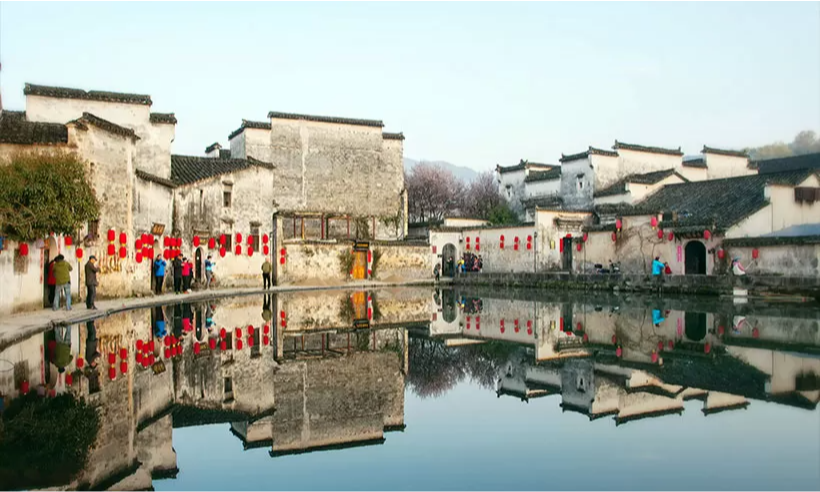 The traditional white-walled and black-roofed houses of Hongcun Village reflecting perfectly in the still water of the historic Moon Pond near Huangshan, during an elite private luxury tour with Lux Orient.