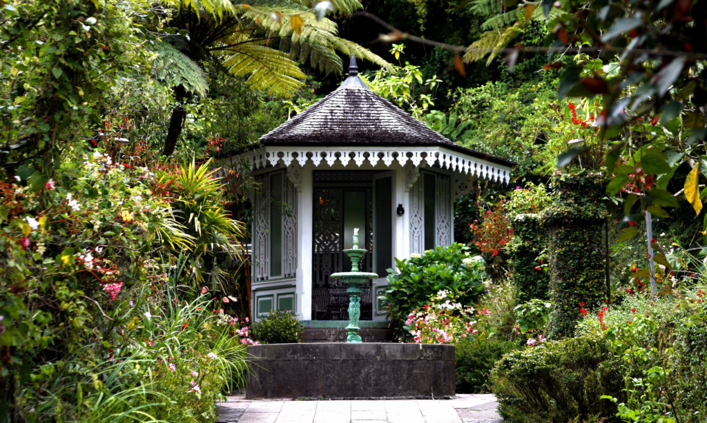 The historic white and green timber facade, ornamental roof carvings, and lush tropical botanical gardens of Maison Folio in Hell-Bourg, La Réunion, during an exclusive private luxury tour with Lux Orient.