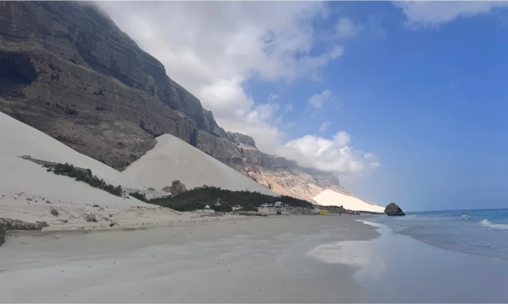 The vast, smooth golden sands and calm turquoise waters of Delisha Beach meeting a natural freshwater lagoon on Socotra Island, Yemen, during an exclusive private luxury tour with Lux Orient.
