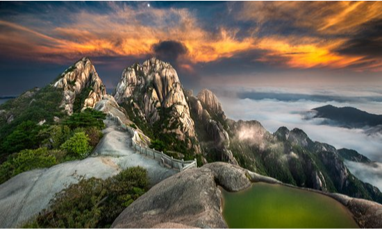 The stone structure of the Cloud Dispelling Pavilion overlooking dramatic granite peaks and swirling white mists in Huangshan, during an elite private luxury mountain tour with Lux Orient.