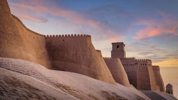 Majestic ancient historic city walls of the old town of Khiva under beautiful colorful sunset twilight. Ancient City Walls Khiva, Itchan Kala, Khiva - Chiva - ????, Xorazm Region, Uzbekistan, Central Asia