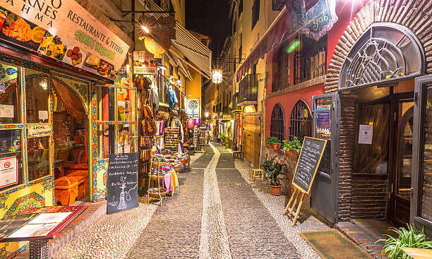 Granada, Andalucia, Spain - April 16, 2016: typical restaurants and shops in a street of the popular old Moorish quarter Albaicin illuminated at night. The historical center of Granada Town.